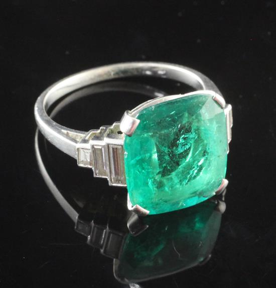 A mid 20th century platinum and single stone emerald dress ring with graduated baguette cut diamond set shoulders, size L.